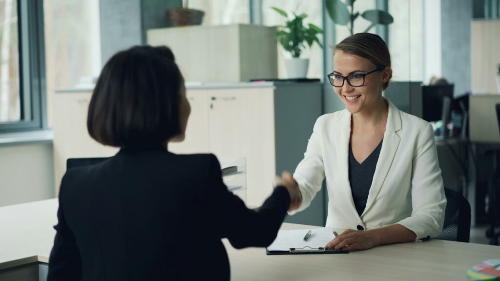 Zwei Frauen geben sich bei einem Bewerbungsgespräch die Hand
